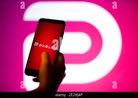 In this photo illustration a Parler App and logo is seen displayed on a smartphone and in the background. The 'free speech' social media platform, Parler, a hit with Trump supporters and an alternative to Twitter, stops working after losing support from Amazon, Apple and Google Stock Photo