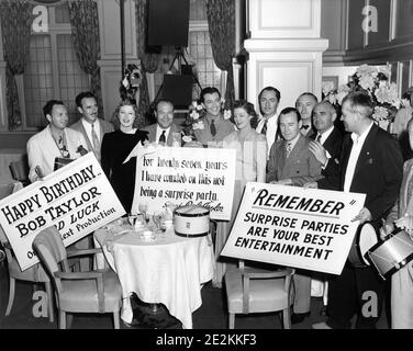 ROBERT TAYOR has surprise Birthday Celebration on August 5th 1939 on the set of his latest film REMEMBER ? with from left Assistant Director AL SHENBERG Director NORMAN Z. McLEOD co-star GREER GARSON Studio Executive EDDIE MANNIX ROBERT TAYLOR and MYRNA LOY and WILLIAM POWELL with Director W.S. VAN DYKE (holding right placard) who were all working on ANOTHER THIN MAN publicity from Metro Goldwyn Mayer Stock Photo
