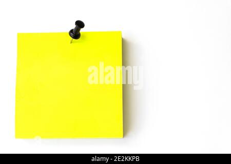 Close-Up Of Yellow Adhesive Notes With Black Pin Against White Background. Yellow reminder note with Black pin Stock Photo