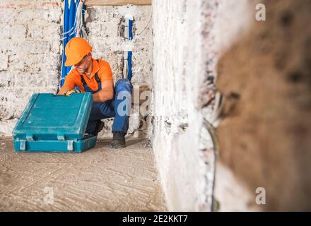 Construction Worker in His 40s Wearing Working Uniform and Hard Hat Inside Remodeled Concrete House Interior Preparing For His Job Stock Photo