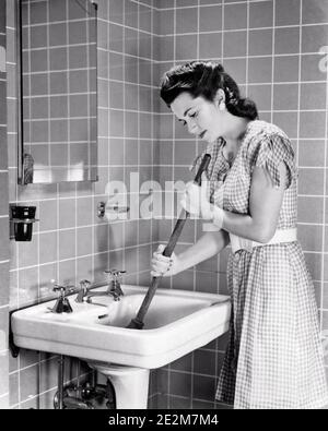 https://l450v.alamy.com/450v/2e2m7m4/1940s-annoyed-exasperated-brunette-woman-housewife-in-the-bathroom-using-a-hand-plunger-to-clear-a-clogged-sink-drain-b16087-har001-hars-chore-strategy-helper-plumbing-a-in-the-to-housewives-using-conceptual-plumbers-clear-clearing-exasperated-plunger-stopped-task-young-adult-woman-black-and-white-caucasian-ethnicity-clogged-har001-old-fashioned-2e2m7m4.jpg