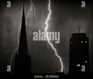 1960s TWO BOLTS OF LIGHTNING IN NIGHT SKY BEHIND SILHOUETTED CHURCH STEEPLE AND OFFICE BUILDING OVER SKYLINE OF READING PA USA - f12562 HAR001 HARS B&W NORTH AMERICA ENERGY NORTH AMERICAN PROPERTY STRENGTH SILHOUETTED AND EXCITEMENT LIGHTNING LOW ANGLE PA POWERFUL STRIKE IN OF BETWEEN NEAR REAL ESTATE CONCEPTUAL STRUCTURES CITIES EDIFICE THUNDERSTORM STEEPLE BOLTS FLASH HIGH VOLTAGE STORMS ATMOSPHERE BLACK AND WHITE BOLT DISCHARGE ELECTROSTATIC HAR001 METEOROLOGY OLD FASHIONED PLASMA THUNDER Stock Photo