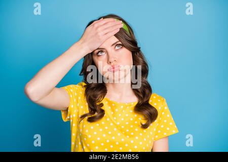 Frustrated tired girl touch forehead with hand look copyspace sigh wear yellow green clothes isolated on blue color background Stock Photo