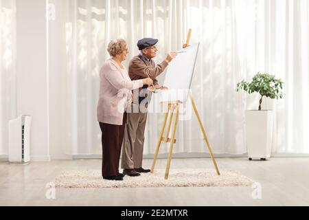 Elderly couple painting with brushes on a canvas at home in a living room Stock Photo