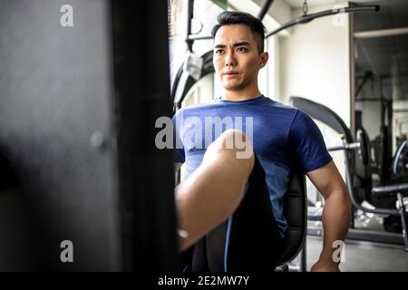 Asian young man doing leg presses in gym Stock Photo