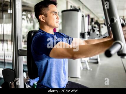 Young man Doing Heavy Weight Exercise For Chest On Machine With Cable In The Gym Stock Photo