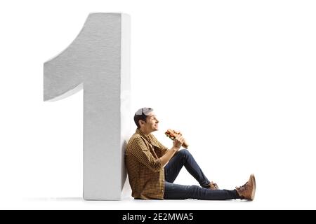 Hungry young man eating a sandwich and leaning on a big number one isolated on white background Stock Photo