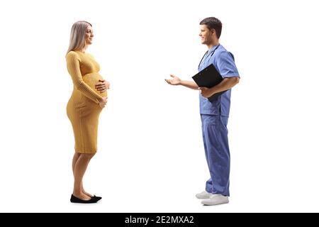 Full length profile shot of a male doctor talking to a pregnant woman in a yellow dress isolated on white background Stock Photo