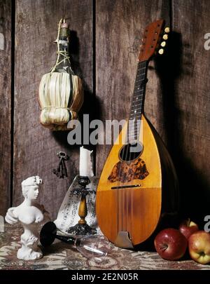 1970s ITALIAN MANDOLIN LUTE CHIANTI BOTTLE APPLES PLASTER BUST OF WOMAN SHEET MUSIC CANDLE AND STAND WOOD STILL LIFE BACKGROUND - ks2871 DAS001 HARS ITALY OF STILL LIFE CHIANTI CULTURE MANDOLIN SYMBOLIC COMMUNICATE LUTE OLD FASHIONED Stock Photo