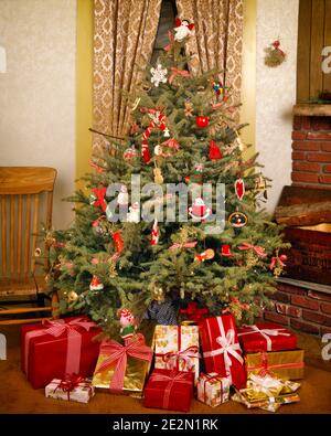 1980s SIMPLE EVERGREEN CHRISTMAS TREE DECORATED WITH HOMEMADE AND HANDMADE ORNAMENTS WRAPPED GIFTS AND PRESENTS AROUND THE BASE - kx9752 TEU001 HARS JOYOUS RELAXATION TOGETHERNESS HANDMADE OLD FASHIONED Stock Photo