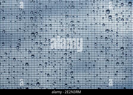 water drops on glass window with mosquito net against gray sky Stock Photo