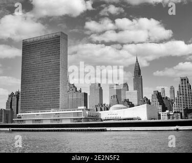 1950s THE UNITED NATIONS BUILDINGS ON EAST SIDE OF MIDTOWN MANHATTAN WITH CHRYSLER BUILDING IN BACKGROUND - r580 HAR001 HARS CHRYSLER EXTERIOR LEADERSHIP OPPORTUNITY AUTHORITY NYC POLITICS 1951 REAL ESTATE CONNECTION CONCEPTUAL NEW YORK STRUCTURES CITIES COMPLEX UN EDIFICE NEW YORK CITY COOPERATION GENERAL ASSEMBLY HEADQUARTERS BLACK AND WHITE EAST RIVER HAR001 OLD FASHIONED UNITED NATIONS Stock Photo