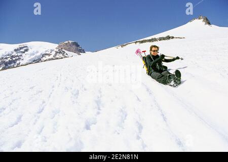 A woman sliding down Muir Snow Field on Mount Rainier, Washington, USA. Stock Photo