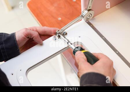 Carpenter working on play furniture. Fixing closers on play kitchen oven door close up Stock Photo