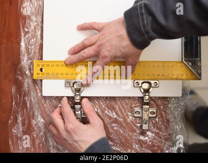 Carpenter at work. Measuring door hinges on wooden door with ruler overhead view Stock Photo