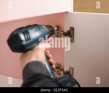 Carpenter at work. Fixing door hinge with screwdriver copyspace Stock Photo