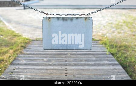 Old gray metal empty plate hanging on chain outdoors, place for text Stock Photo