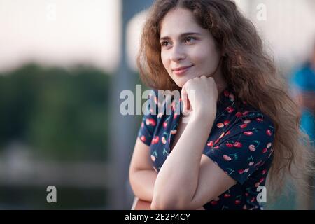 a girl in a beautiful blue dress with cherries with a good mood and a charming smile walks in the city in summer Stock Photo