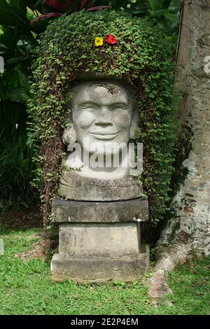 Indonesia Bali Ubud Buddha statue in lotus seat with hibiscus flowers ...