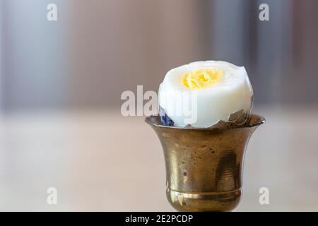Hard boiled Quail egg in brass egg holder with shell cracked open ready to be eaten Stock Photo