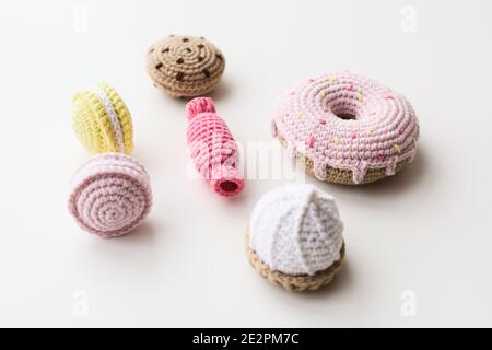 Stylish amigurumi toy sweets. Knitted cakes, candies and donuts on white background copy space Stock Photo