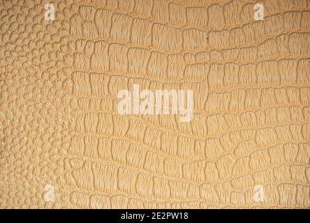 A fragment of the skin of a reptile artificially colored in gold. Background, texture, pattern, blank. Stock Photo