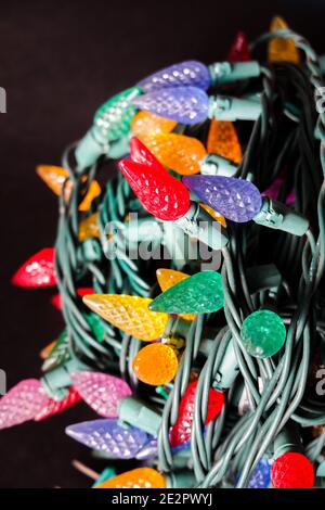 Colorful Christmas lights rolled up  on a black background Stock Photo