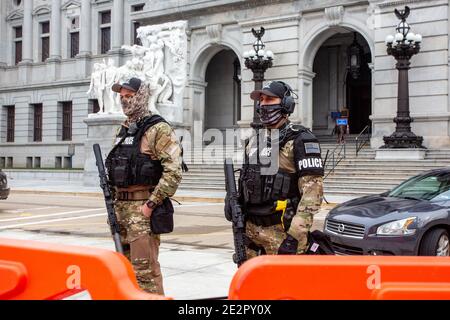 Capitol Police stand guard behind orange barricades at the Pennsylvania Capitol.An FBI bulletin warned that armed protests were planned at all the 50 state capitols in the days leading up to President-elect Joe Biden's inauguration. Stock Photo