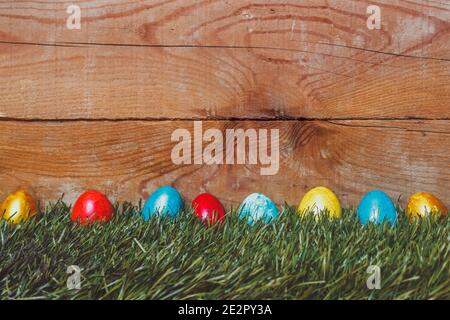 Colorful Easter eggs on the grass. Decorated easter eggs on placed on green grass against the wooden desk with copy space Stock Photo