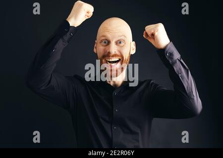 A happy man with a Ginger beard in Front of a black background Stock Photo