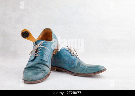 Pair of old leather dirty shoes, crumpled blue torn discarded boots with laces, shoe brush, horizontal, copy space, side view, place for text on white Stock Photo
