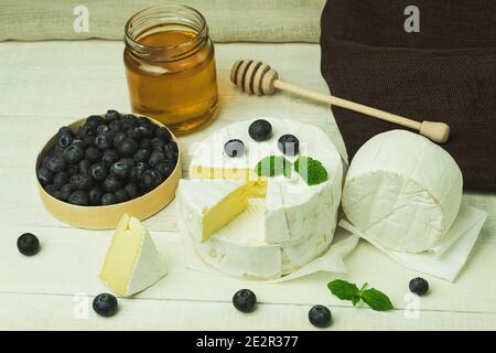 Camamber cheese is a type of soft, fatty cheese made from cow's milk. Food banner for text or design. Side view photo of camembert cheese and fresh bl Stock Photo