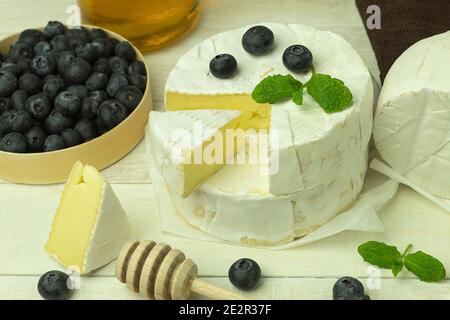 Camamber cheese is a type of soft, fatty cheese made from cow's milk. Food banner for text or design. Side view photo of camembert cheese and fresh bl Stock Photo