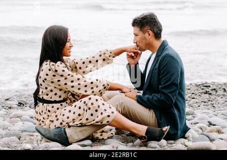Young couple in love, attractive man and woman enjoying a romantic date on the beach, man kissing woman's hand