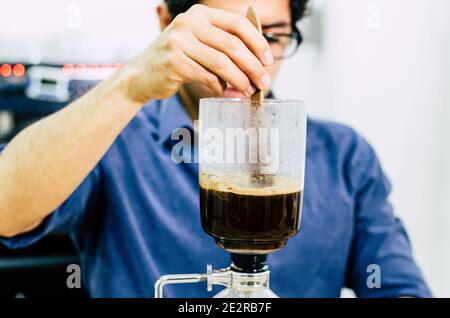 Professional coffee maker - Barista using coffee siphon brewing hot espresso at coffee shop Stock Photo