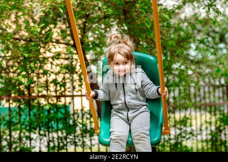 Laughing child on swing in summer park.plays children's games, runs and jumps. carefree childhood. Stock Photo