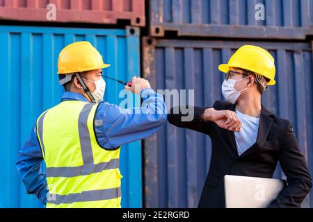 Asian industry construction site worker and foreman wearing hygiene face mask elbow bump greeting adaptation to prevent Coronavirus or Covid-19 spread Stock Photo