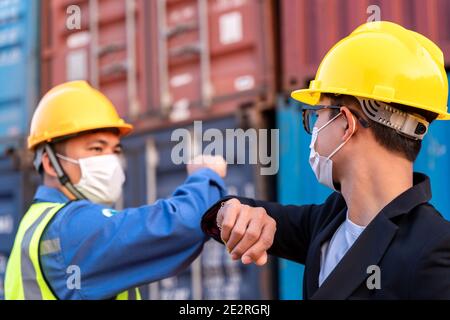 Asian industry construction site worker and foreman wearing hygiene face mask elbow bump greeting adaptation to prevent Coronavirus or Covid-19 spread Stock Photo