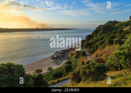 Matakana Island, New Zealand, and the entrance to Tauranga Harbour, seen from Mount Maunganui. Smoke is rising from a fire in Matakana's pine forests Stock Photo