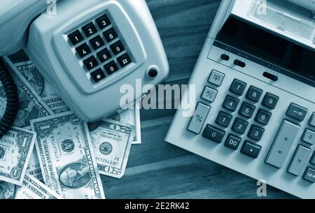 Old fashioned calculator, telephone and dollars on desk Stock Photo
