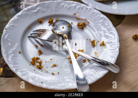 Empty dirty plate with spoon and fork on the table after breakfast Stock Photo