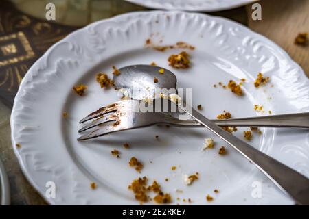 Empty dirty plate with spoon and fork on the table after breakfast Stock Photo