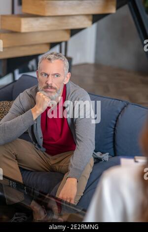 Thoughtful grey-haired man having an interesting conversation Stock Photo