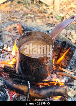 Coffee is prepared in cezve on fire. Vertical image. Stock Photo