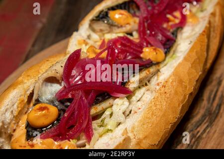 A delicious Grilled Mackerel fish Baguette on a wooden kitchen table top Stock Photo