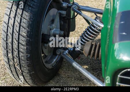 Close up detail of the front suspension and wheel on a British racing green 1960s Lotus Seven lightweight open top sports car Stock Photo