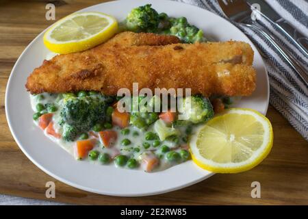 breaded fish with mixed vegetables in a creamy sauce Stock Photo