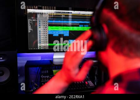 White young DJ is recording a new track in the stereo studio workplace using song mixer and microphone. Stock Photo