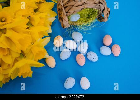 Happy Easter. Easter holiday decorations on trendy colored classic blue background. Creative spring composition with Easter elements - flowers and eggs in basket. Celebrating Easter concept at spring. Stock Photo