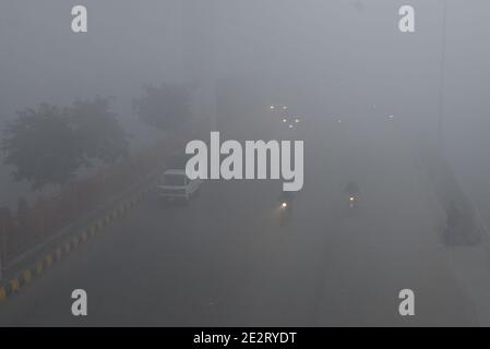 Lahore, Pakistan. 15th Jan 2021. Pakistani Commuters and people make their way amid dense fog on a cold winter morning in Lahore. The intensity of the fog, visibility was reduced to zero, making it difficult for vehicles to maneuver on the roads. The traffic police have issued safety guidelines for people after the fog rolled into the city. Credit: Pacific Press Media Production Corp./Alamy Live News Stock Photo